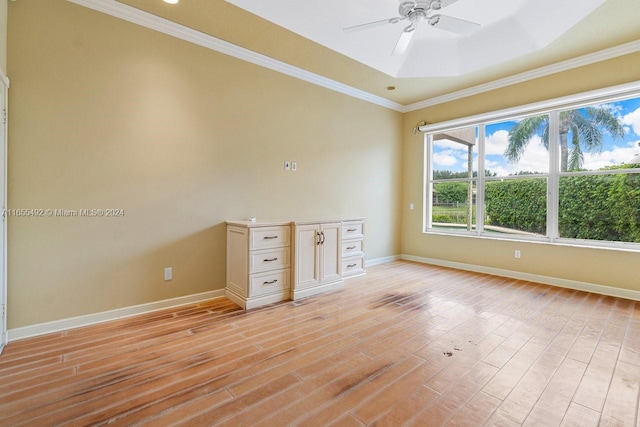 unfurnished office featuring crown molding, light hardwood / wood-style flooring, ceiling fan, and a tray ceiling