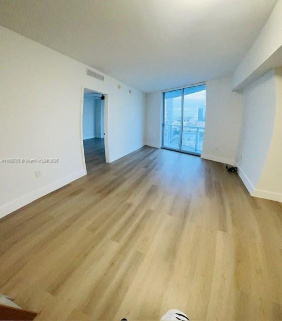 unfurnished room with light hardwood / wood-style flooring and floor to ceiling windows