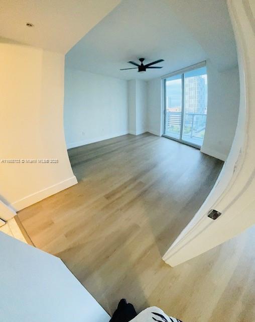 empty room featuring hardwood / wood-style floors, ceiling fan, and floor to ceiling windows