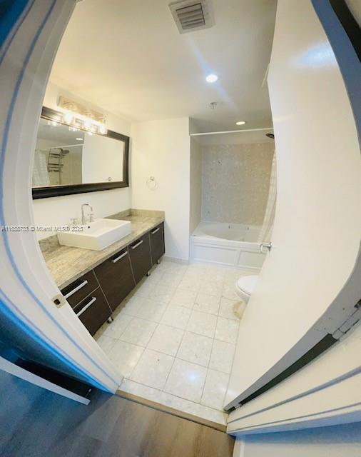 full bathroom with shower / bath combination with curtain, toilet, and vanity