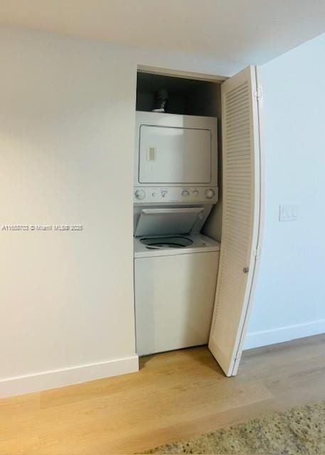 washroom with light hardwood / wood-style floors and stacked washer / dryer