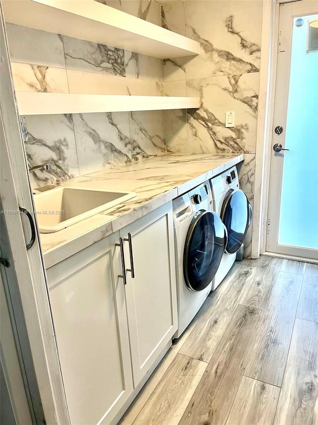 laundry room featuring washing machine and dryer, sink, and light hardwood / wood-style flooring