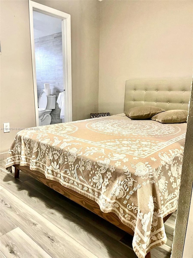 bedroom featuring wood-type flooring and ensuite bath