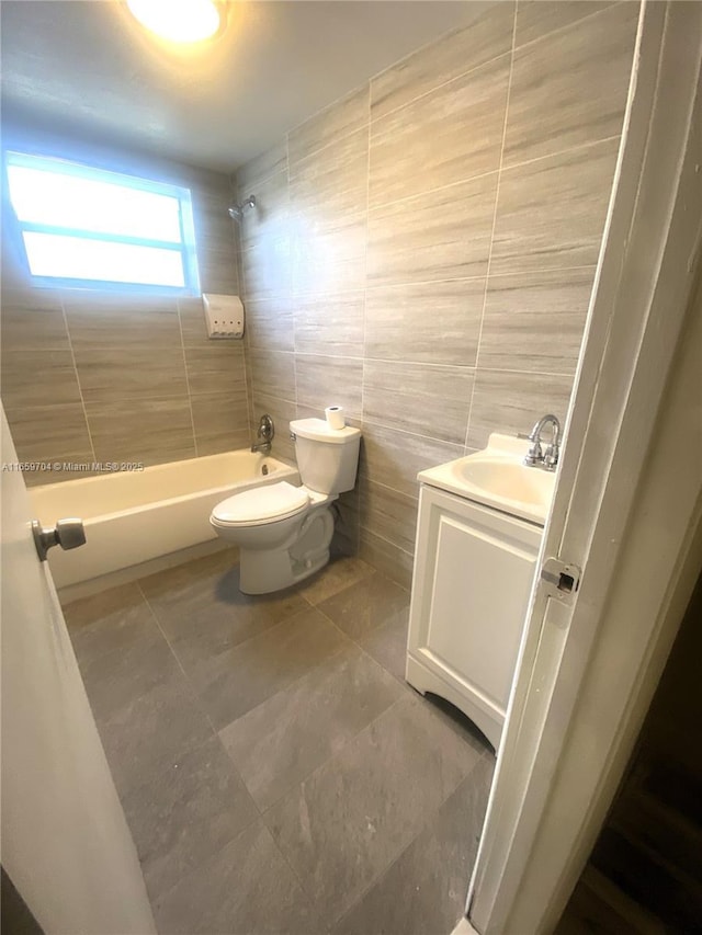 full bathroom with tile patterned floors, toilet, tiled shower / bath, tile walls, and vanity