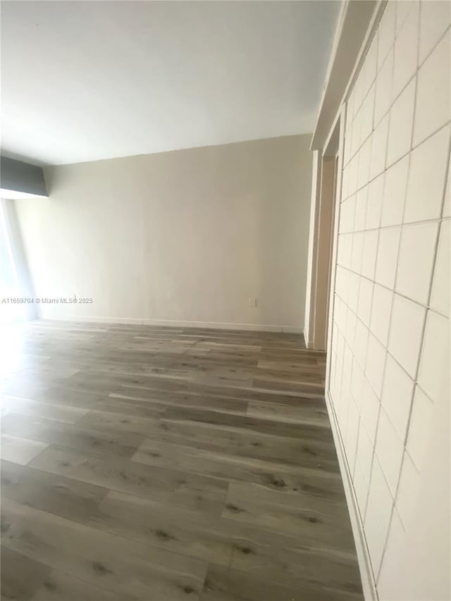 unfurnished room featuring dark wood-type flooring and tile walls