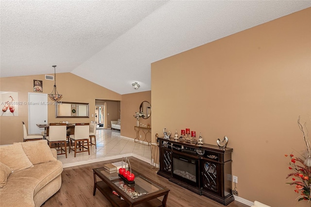 living room featuring lofted ceiling, hardwood / wood-style flooring, and a textured ceiling