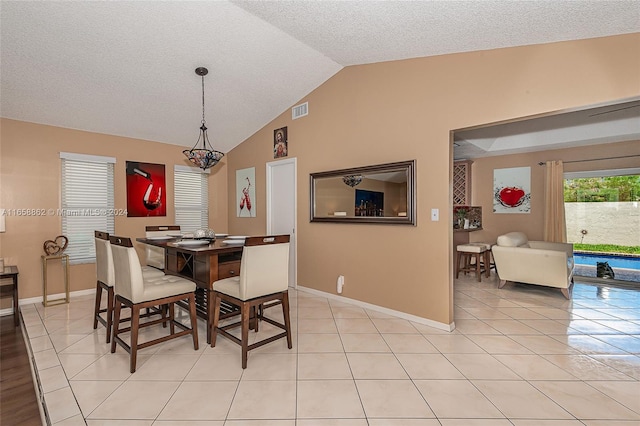 tiled dining space with vaulted ceiling and a textured ceiling