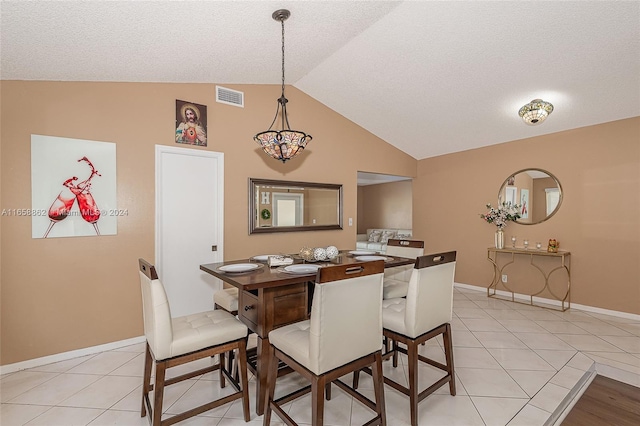 dining room featuring lofted ceiling, light tile patterned floors, and a textured ceiling