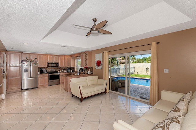 tiled living room with ceiling fan, a raised ceiling, and a textured ceiling