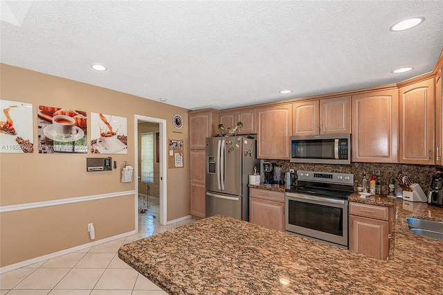 kitchen with a textured ceiling, stainless steel appliances, light tile patterned floors, and tasteful backsplash