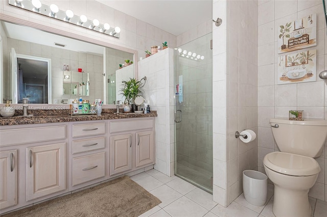 bathroom with vanity, walk in shower, tile patterned flooring, tile walls, and toilet