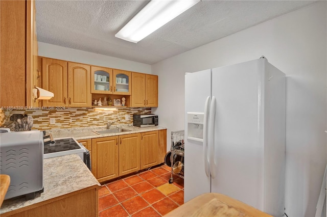 kitchen with backsplash, tile patterned floors, stainless steel appliances, sink, and a textured ceiling