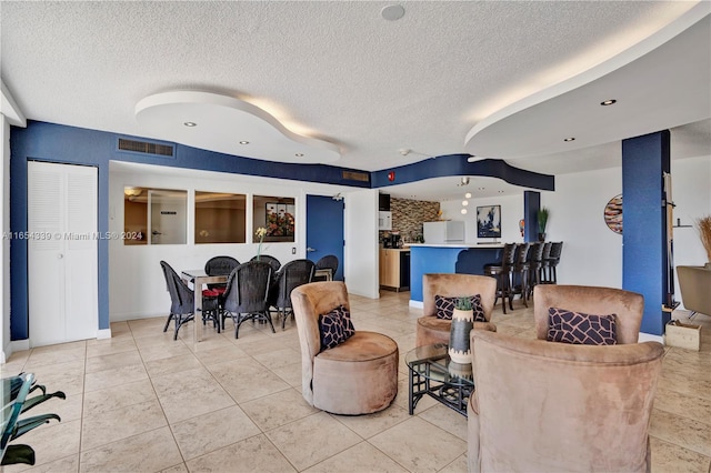 living room with a textured ceiling and light tile patterned flooring