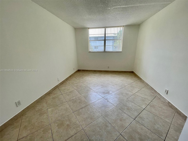 empty room featuring a textured ceiling and light tile patterned floors