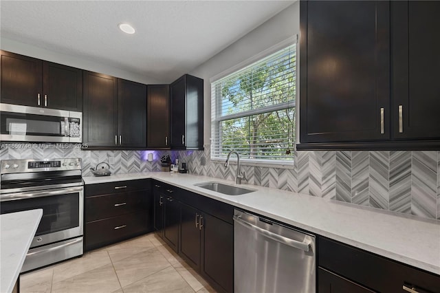 kitchen with stainless steel appliances, a sink, light countertops, and decorative backsplash