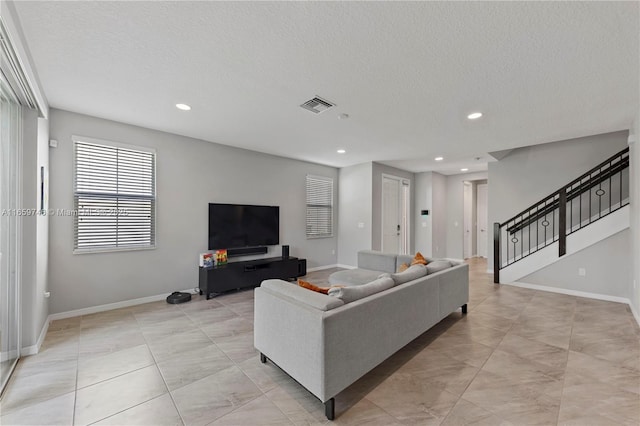 living room featuring baseboards, visible vents, stairs, a textured ceiling, and recessed lighting