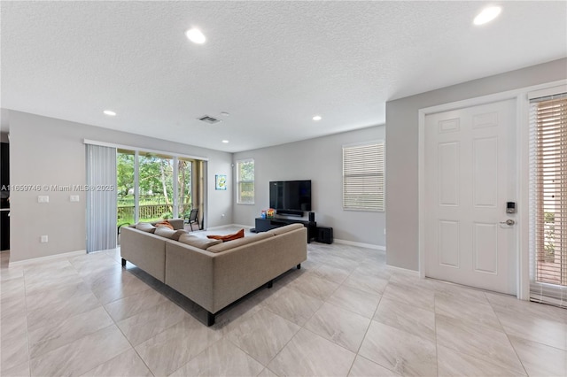 living area featuring visible vents, baseboards, a textured ceiling, and recessed lighting