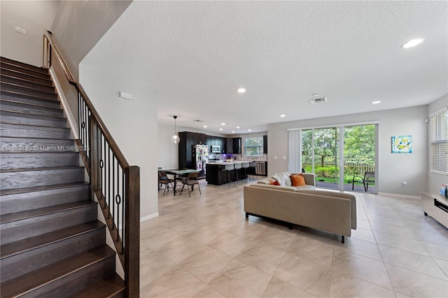 living area featuring recessed lighting, stairway, and a textured ceiling