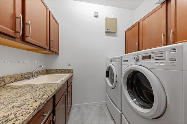 clothes washing area with cabinet space, baseboards, a sink, and independent washer and dryer