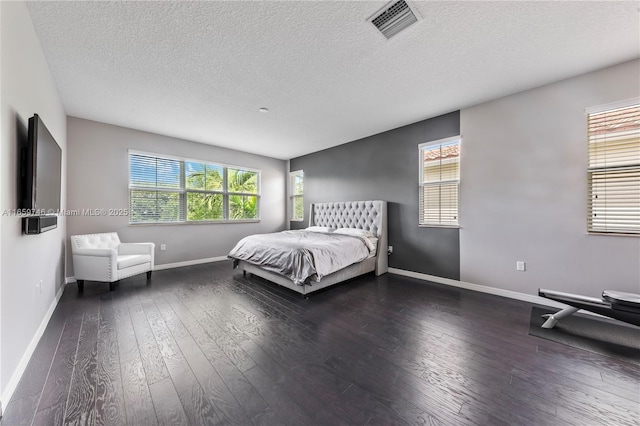 unfurnished bedroom featuring wood-type flooring, multiple windows, and visible vents