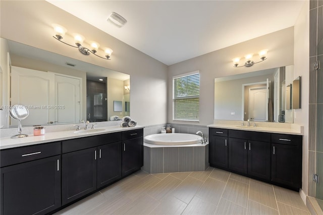 bathroom featuring a garden tub, a shower stall, two vanities, and a sink