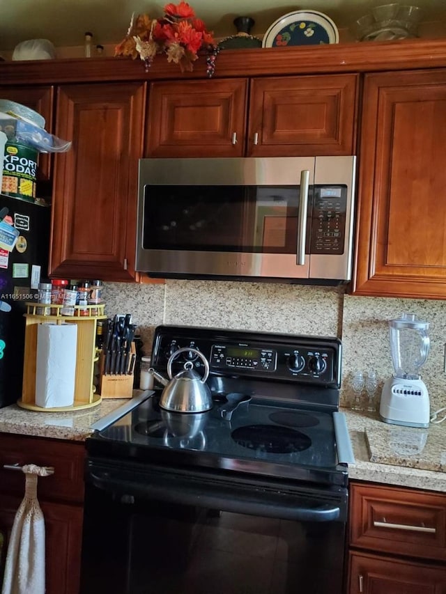 kitchen featuring black range with electric cooktop, tasteful backsplash, and light stone countertops