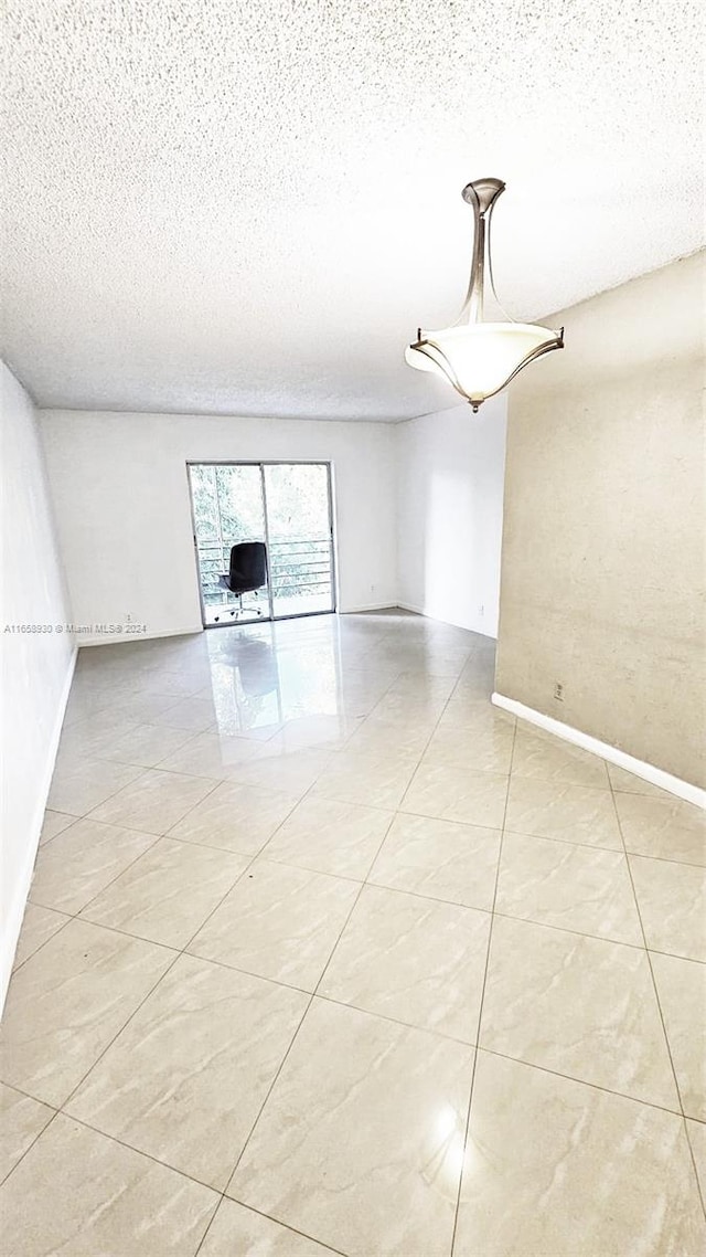 tiled spare room featuring a textured ceiling