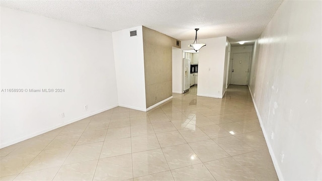 empty room with a textured ceiling and light tile patterned floors