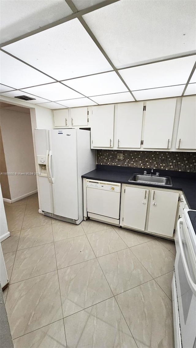 kitchen with white appliances, light tile patterned floors, tasteful backsplash, sink, and white cabinets