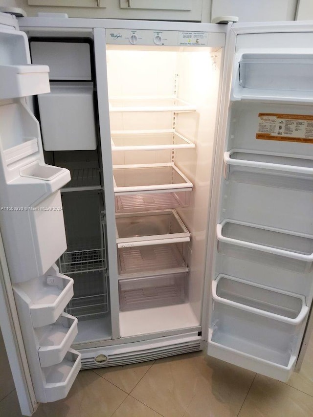 interior details featuring light tile patterned floors and refrigerator