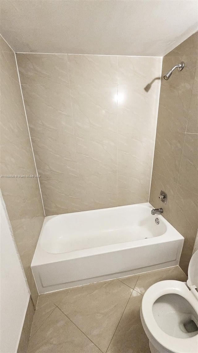 bathroom featuring tiled shower / bath combo, toilet, and tile patterned floors