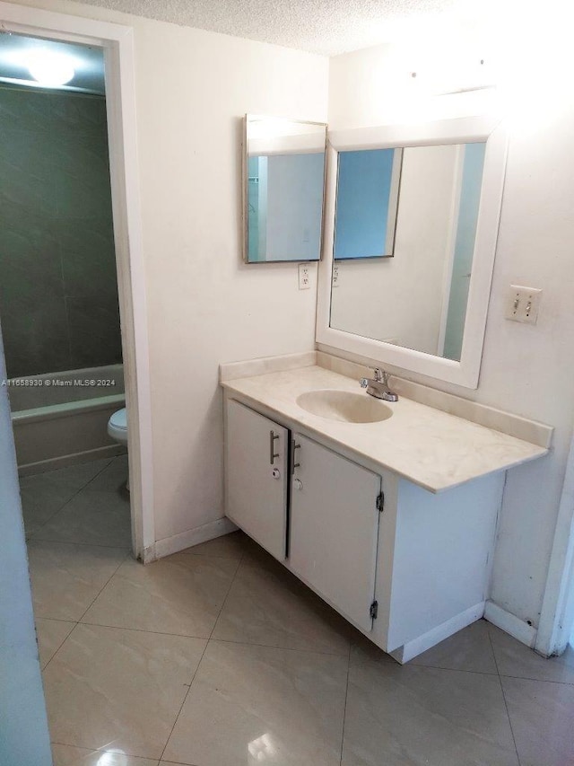 bathroom featuring vanity, toilet, tile patterned flooring, and a textured ceiling