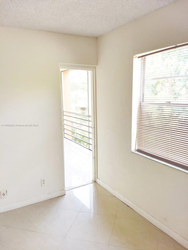 tiled empty room featuring a textured ceiling