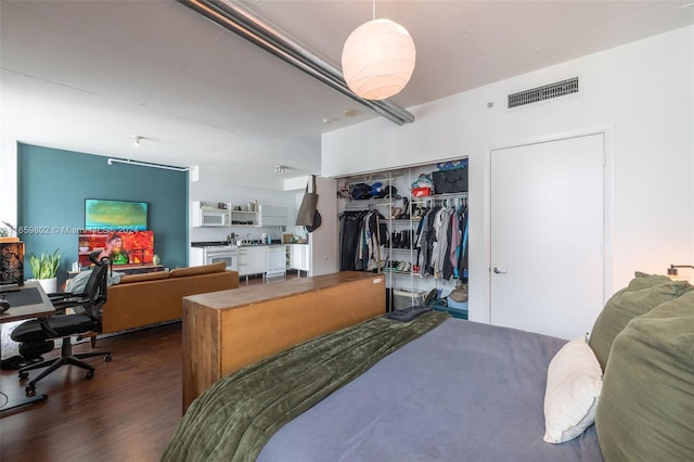 bedroom with dark hardwood / wood-style floors and a closet