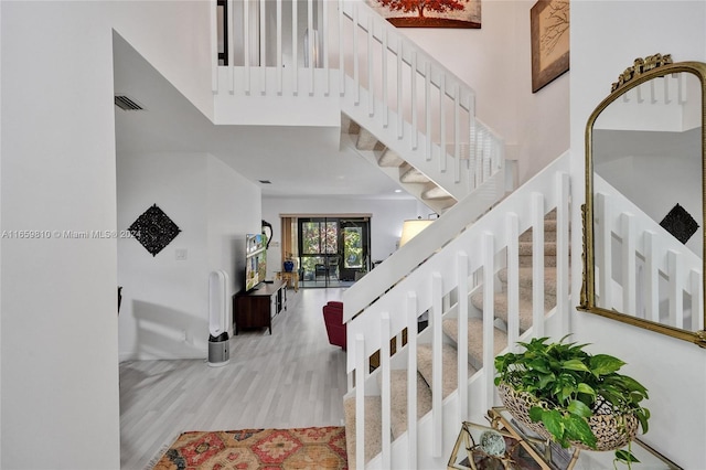 stairs featuring a towering ceiling and wood-type flooring