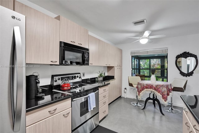 kitchen with stainless steel appliances, dark stone countertops, ceiling fan, and light brown cabinetry