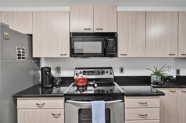 kitchen featuring dark stone countertops, light brown cabinets, and stainless steel appliances