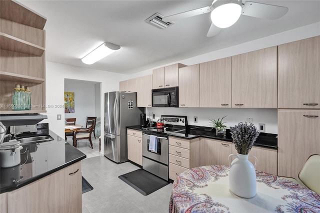 kitchen with dark stone countertops, appliances with stainless steel finishes, sink, light brown cabinets, and ceiling fan