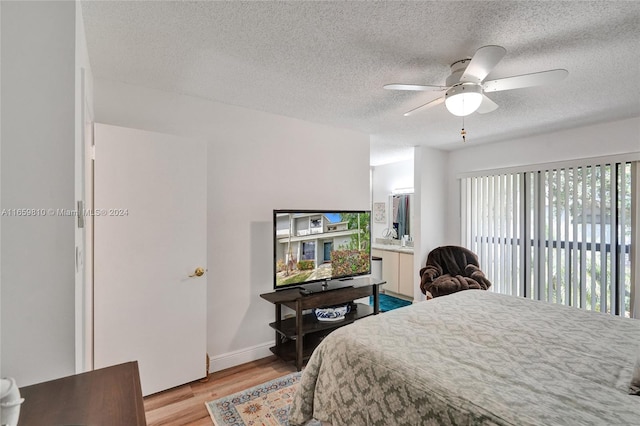 bedroom with a textured ceiling, ceiling fan, and light wood-type flooring