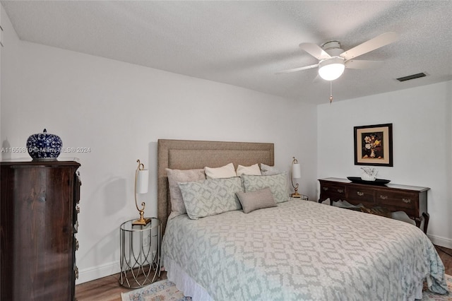 bedroom with a textured ceiling, hardwood / wood-style flooring, and ceiling fan