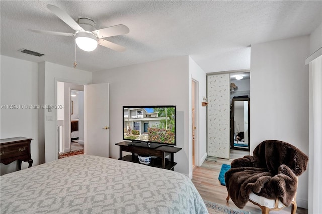 bedroom featuring a textured ceiling, ceiling fan, and light wood-type flooring