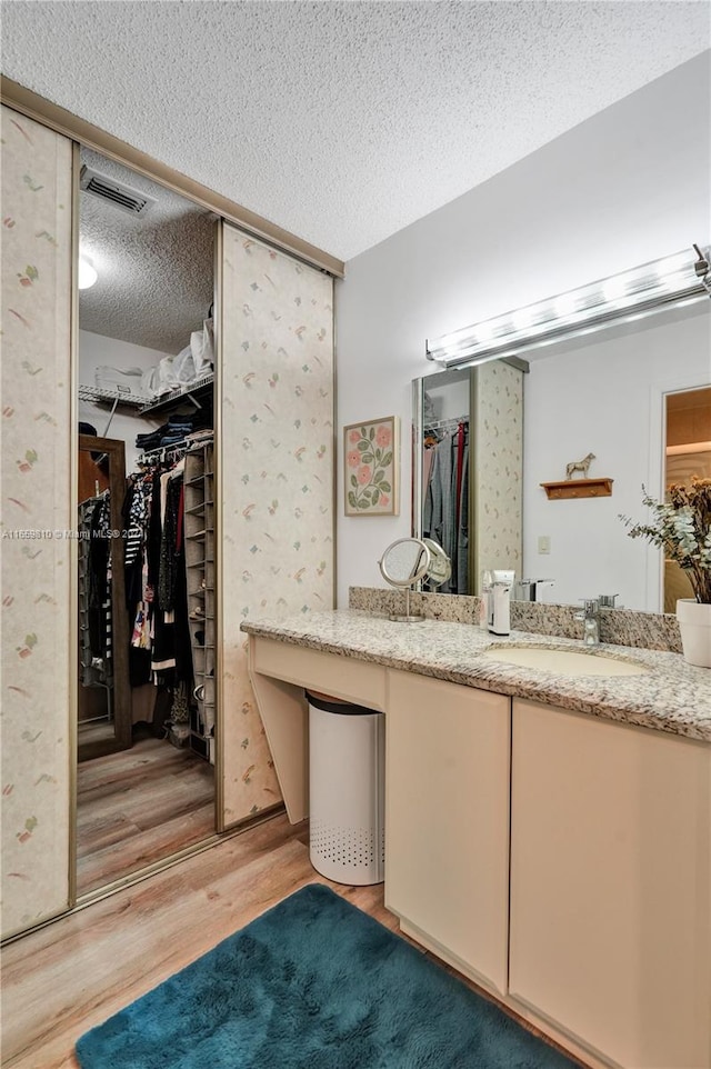 bathroom featuring wood-type flooring, vanity, and a textured ceiling