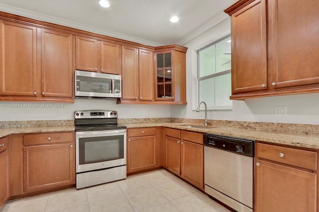 kitchen featuring light stone counters, ornamental molding, light tile patterned floors, sink, and appliances with stainless steel finishes