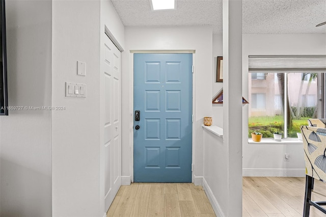 foyer entrance with a textured ceiling and light hardwood / wood-style flooring