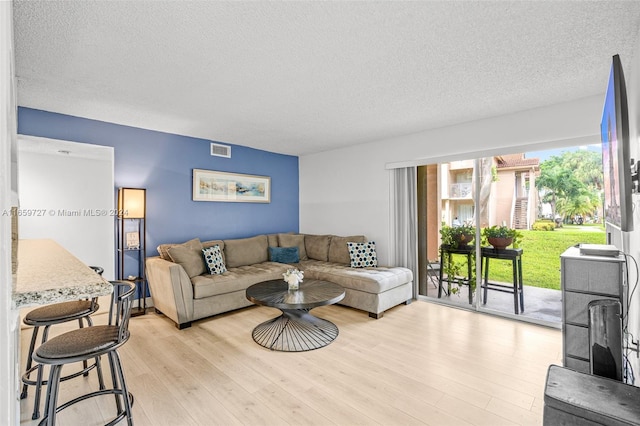 living room with a wealth of natural light, light hardwood / wood-style floors, and a textured ceiling