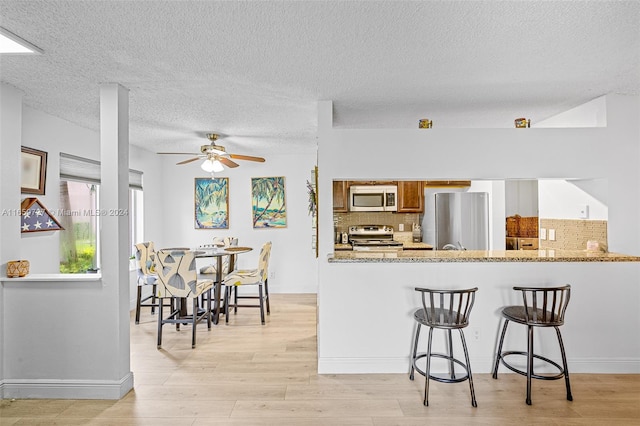 kitchen featuring stainless steel appliances, light stone counters, and decorative backsplash