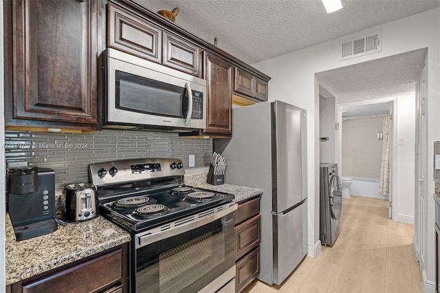 kitchen with independent washer and dryer, a textured ceiling, light hardwood / wood-style flooring, stainless steel appliances, and decorative backsplash