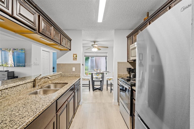 kitchen featuring tasteful backsplash, stainless steel appliances, sink, ceiling fan, and light wood-type flooring