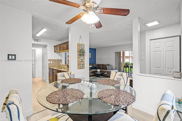 dining space featuring a textured ceiling, ceiling fan, and light hardwood / wood-style floors