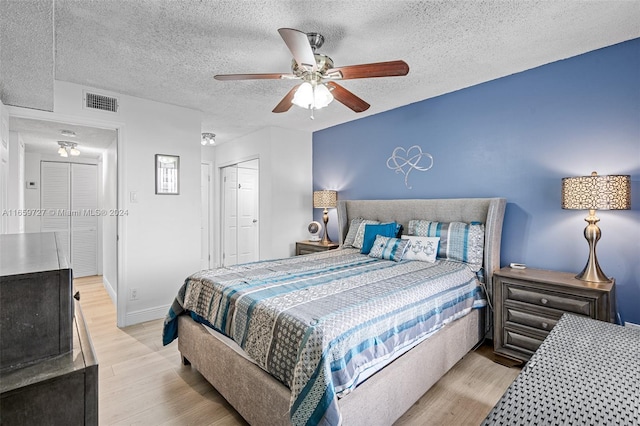 bedroom with a textured ceiling, light hardwood / wood-style flooring, ceiling fan, and a closet